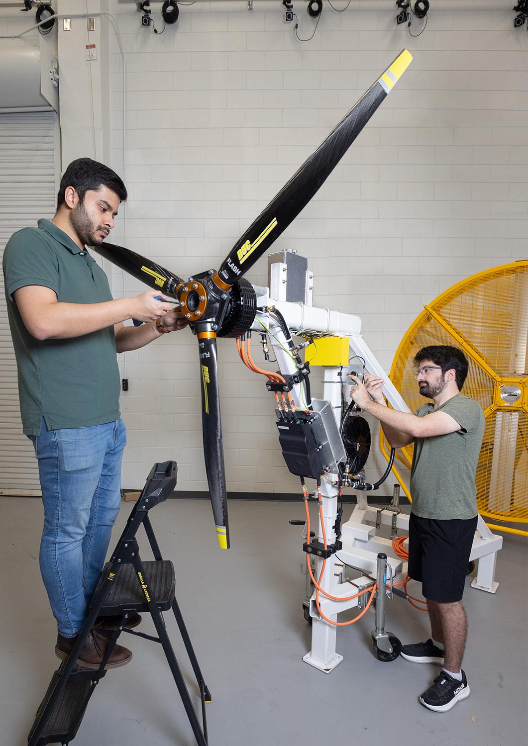 Two people work on a propeller and motor in the lab