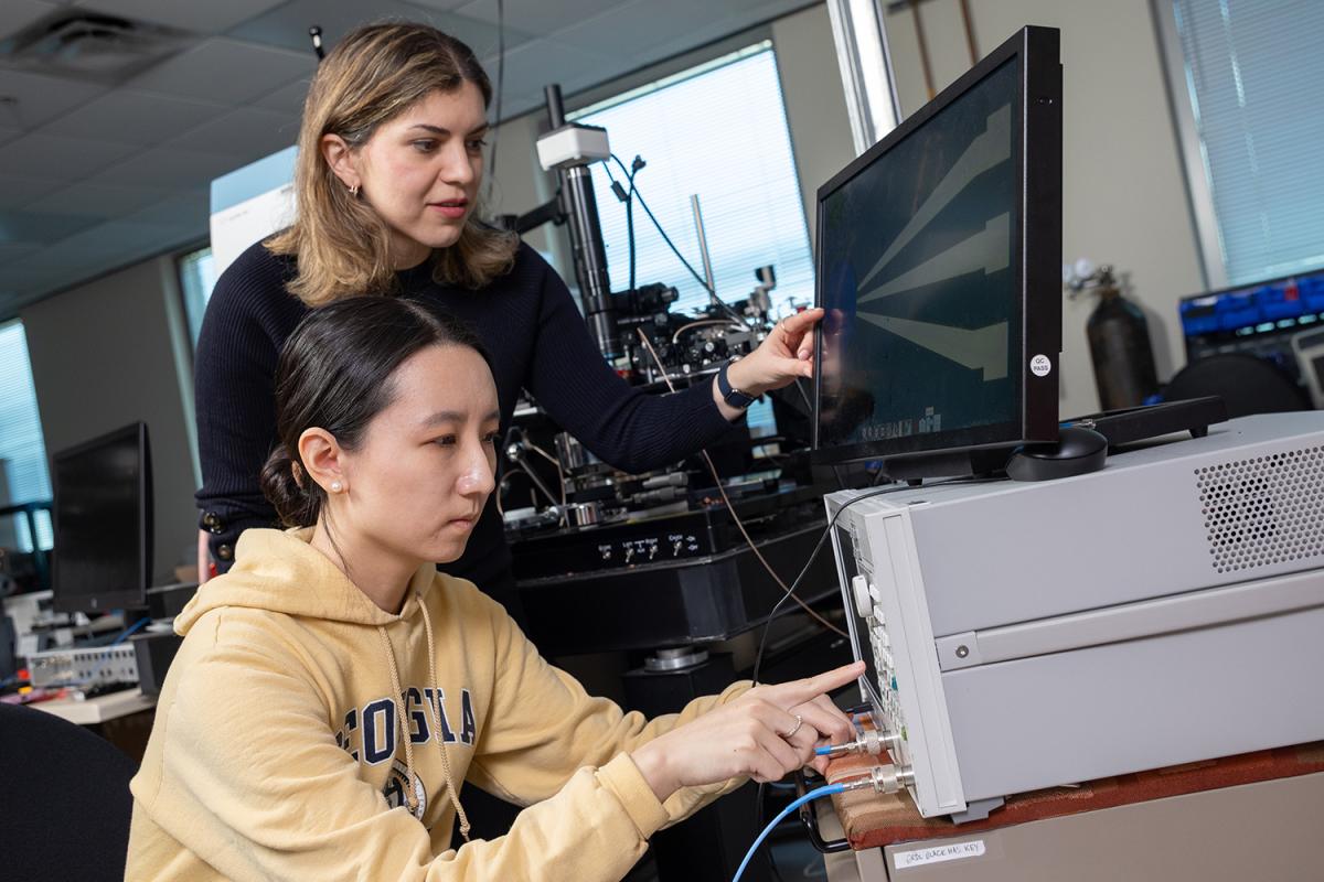 two people look at a computer screen in the lab