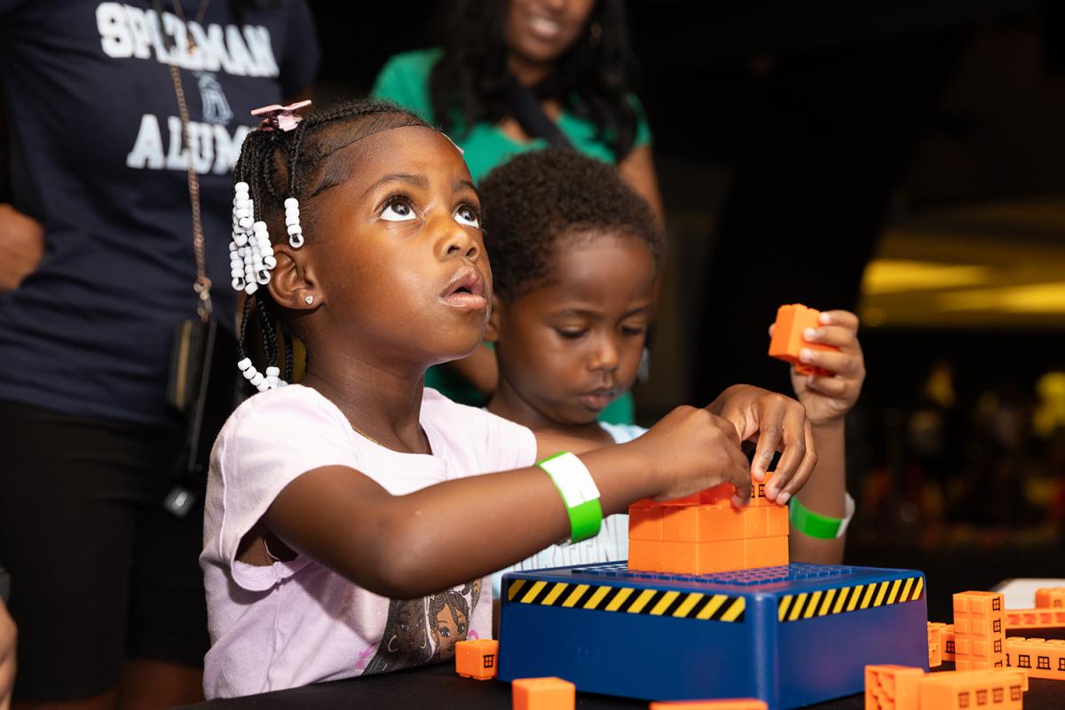 A young student listens while she builds with blocks at STEM Fest.