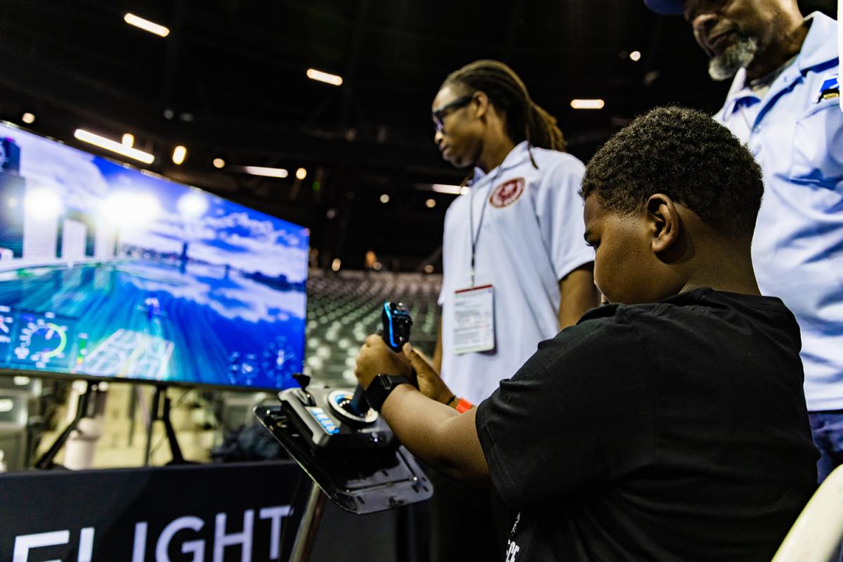 A student flies a plane in a computer simulator at STEM Fest.