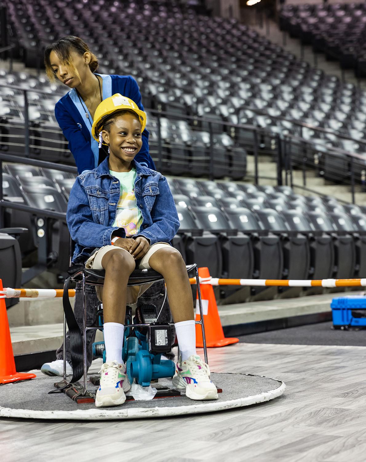 A young student rides a "hovercraft" at STEM Fest.