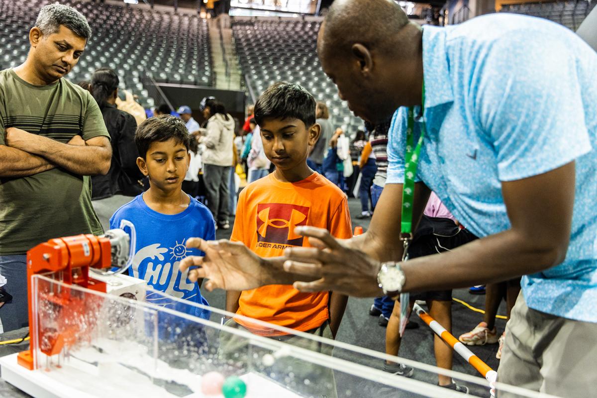 A volunteer explains wave energy to kids at STEM Fest 2025.