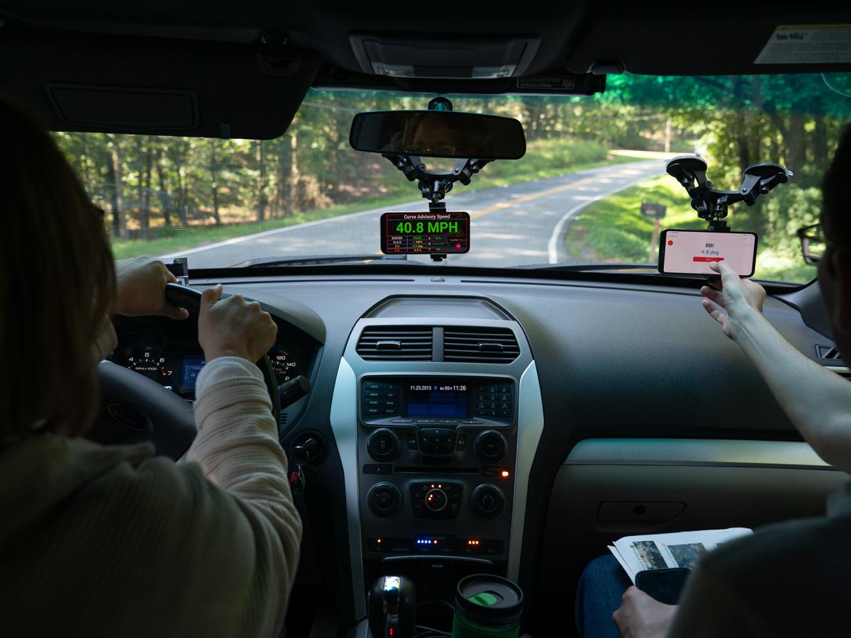 A smartphone mounted on a car dashboard shows a calculated curve advisory speed during tests in Forsyth County, Georgia.