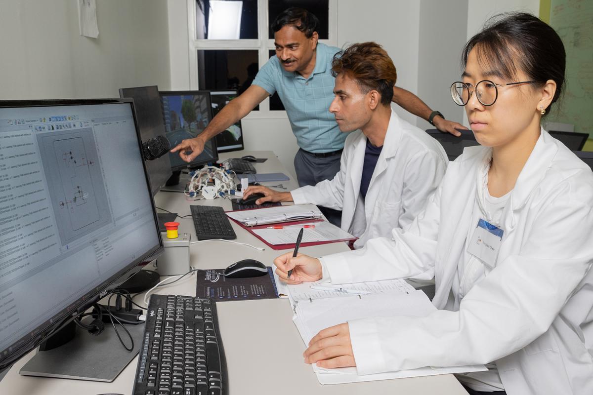three people look at data on computer screens