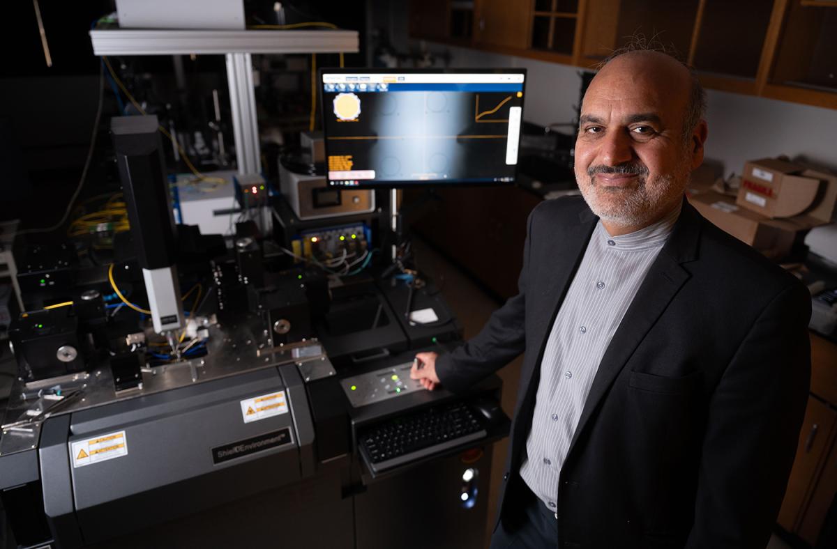 a person stands in front of lab equipment and a computer screen