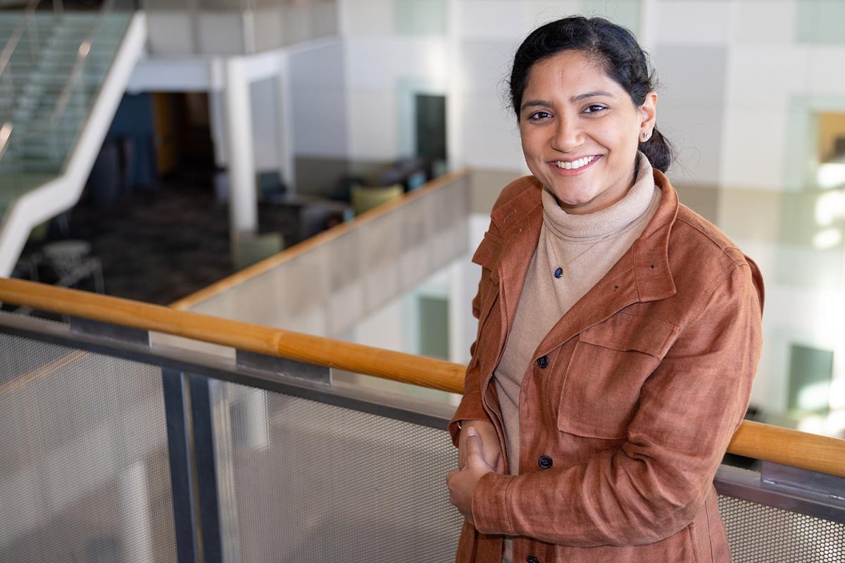 Divya Mahajan stands at the railing of the atrium in the Klaus building