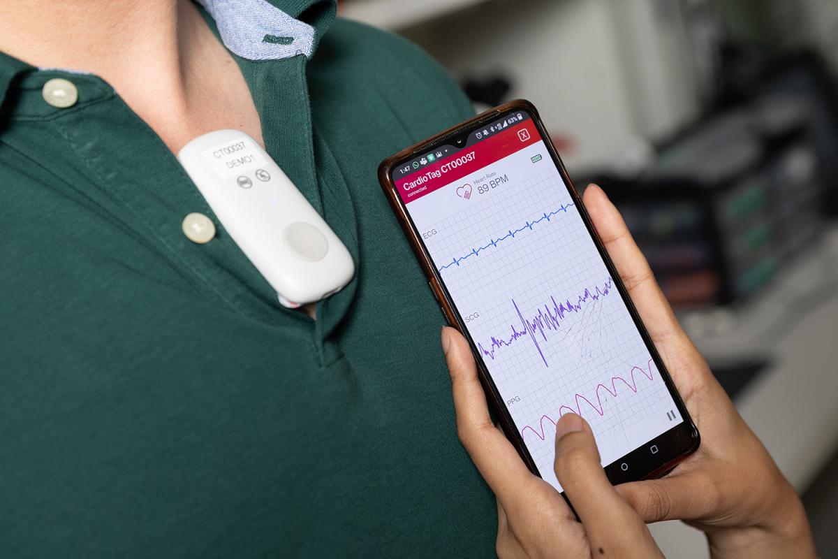 closeup of cardiac data on a smartphone with a device on the user in the background