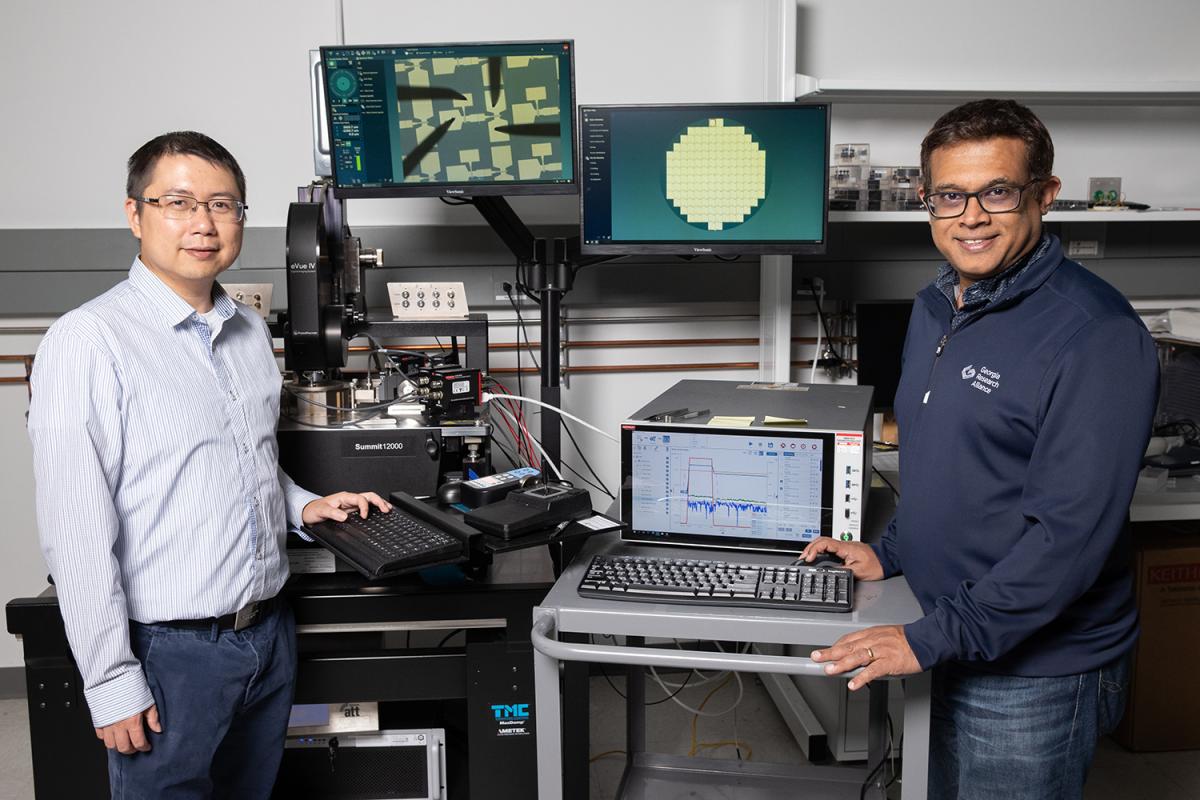 two people stand in a lab with computers and images of chips behind them