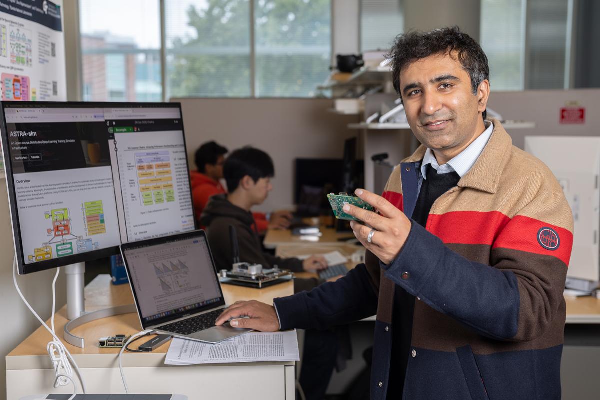 a person holding a circuitboard with computer screens of data in the background