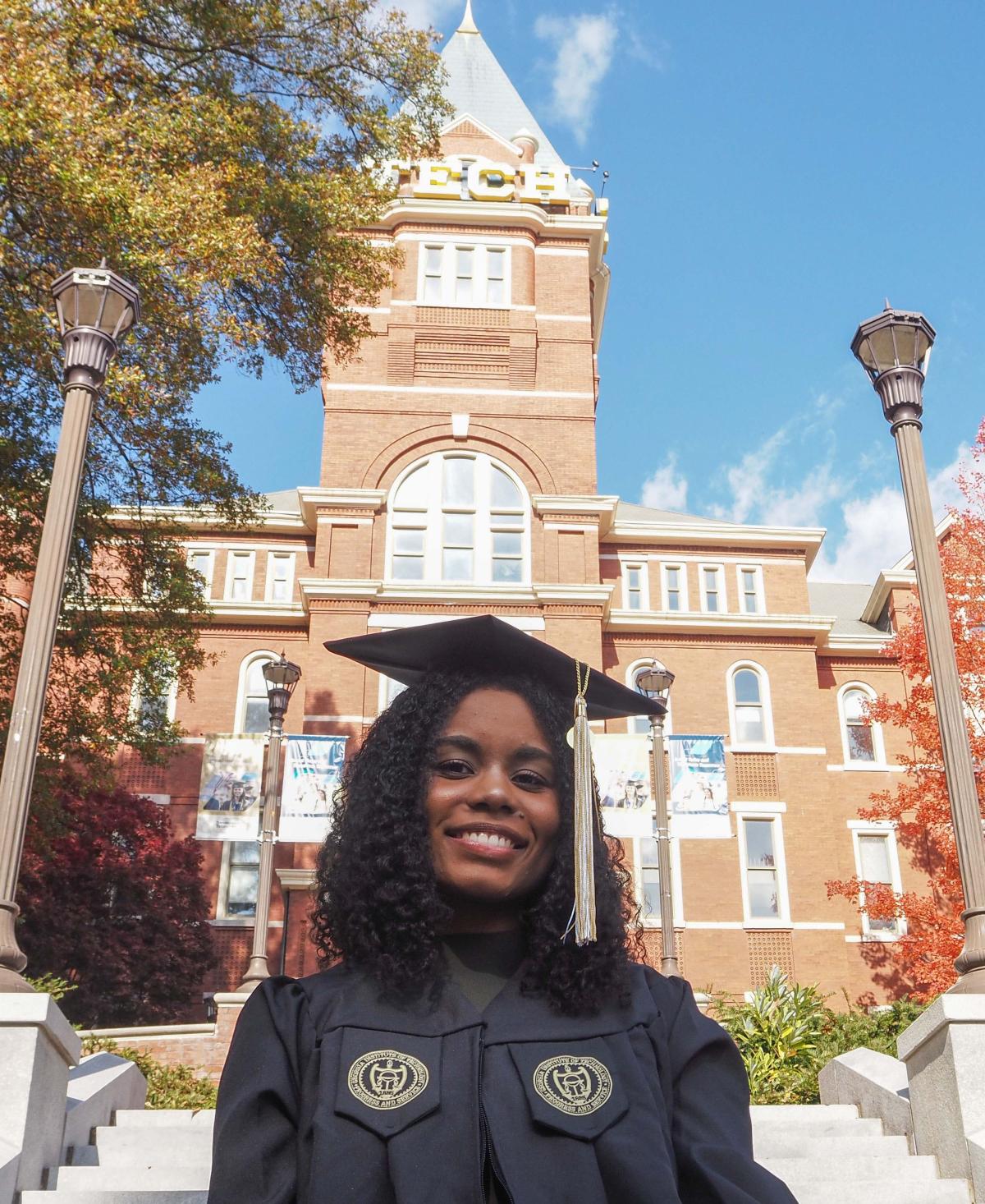 woman standing in front of Tech Tower while wearing graduation gown
