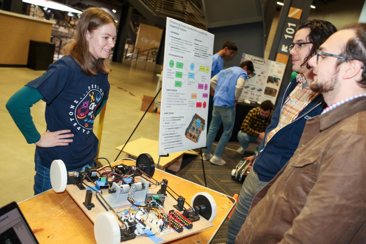 woman talking to two mean with robot with wheels on table