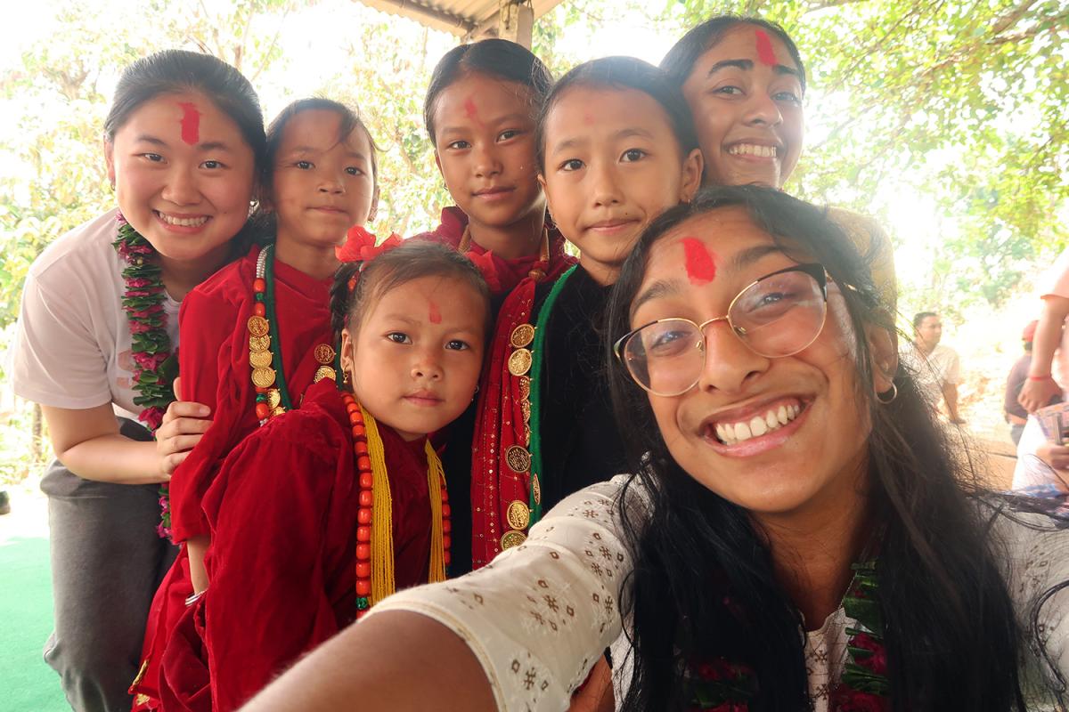 The three EWB Georgia Tech team members taking a selfie with a group of kids in Nepal.