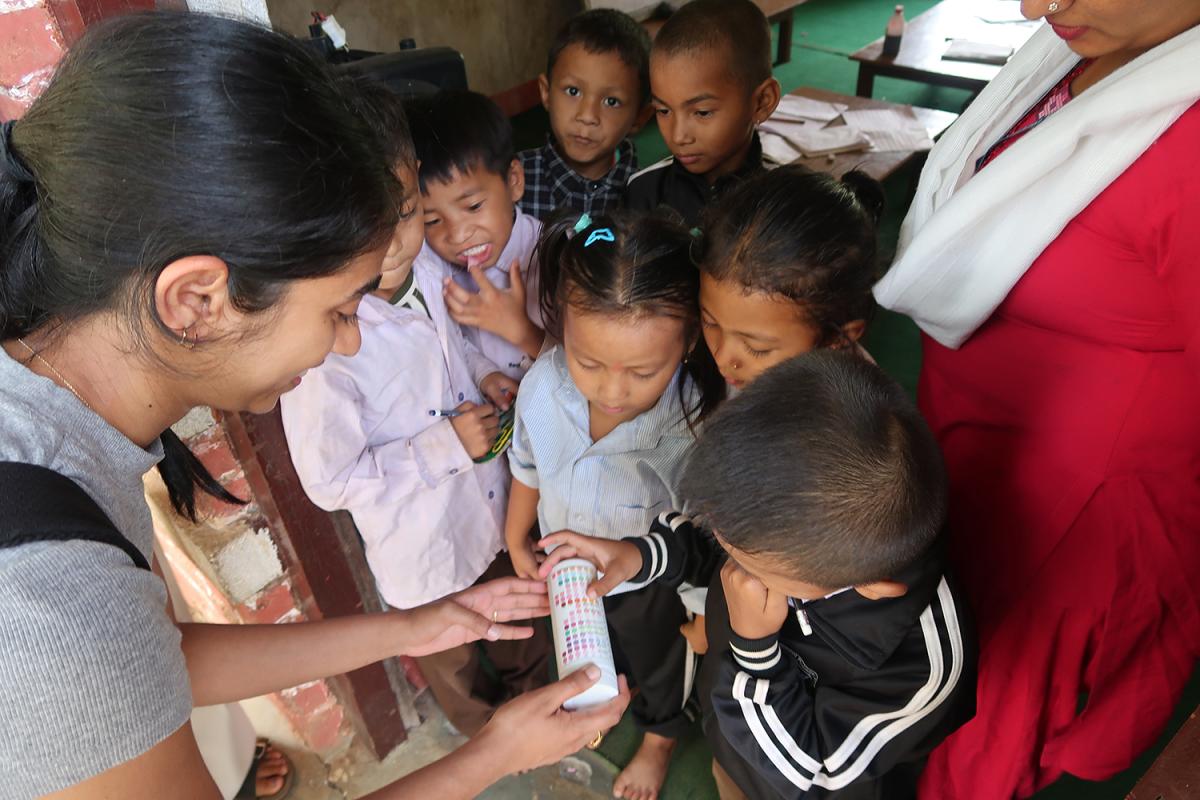 A student shows water testing strips to a group of children in Chisopani Bhirkhe, Nepal.
