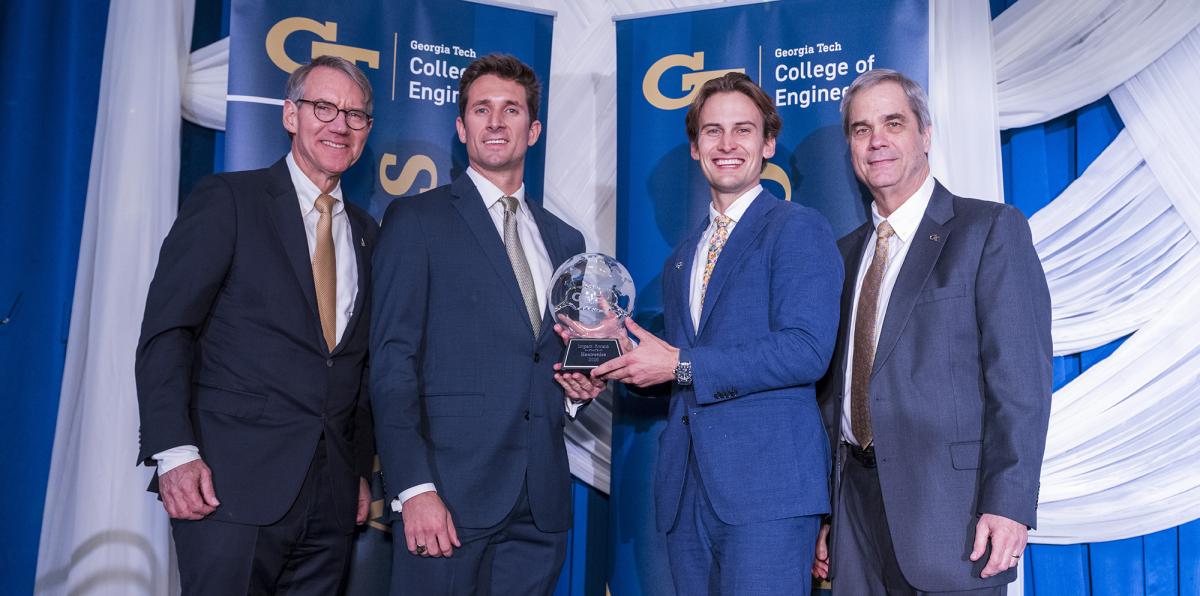 Curt Lary and Nicholas Mulka from Hex hold their Dean's Impact Award alongside emcee Jim Borders and interim Dean Doug Williams.