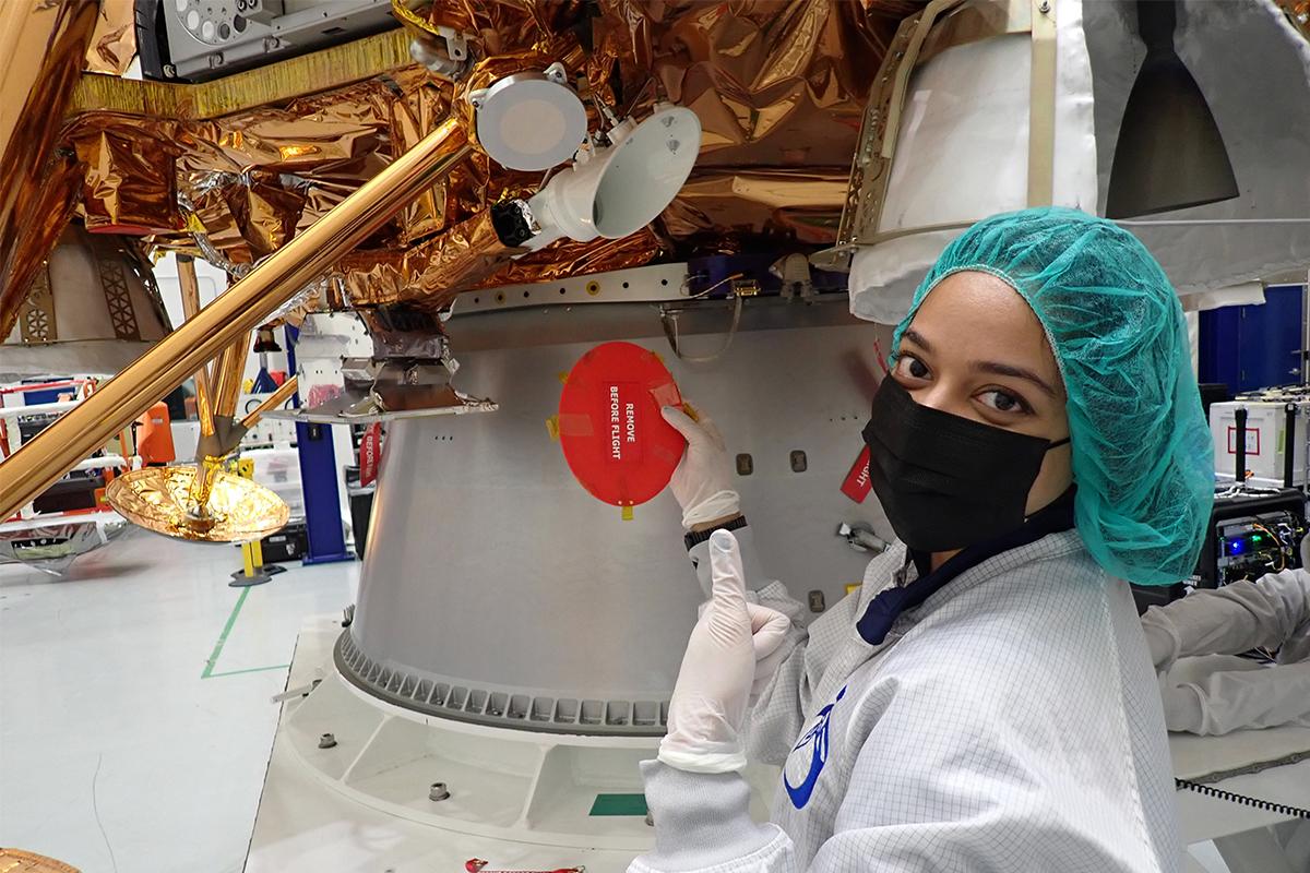 Farah Zuberi in a labcoat stands next to the Blue Ghost lunar lander