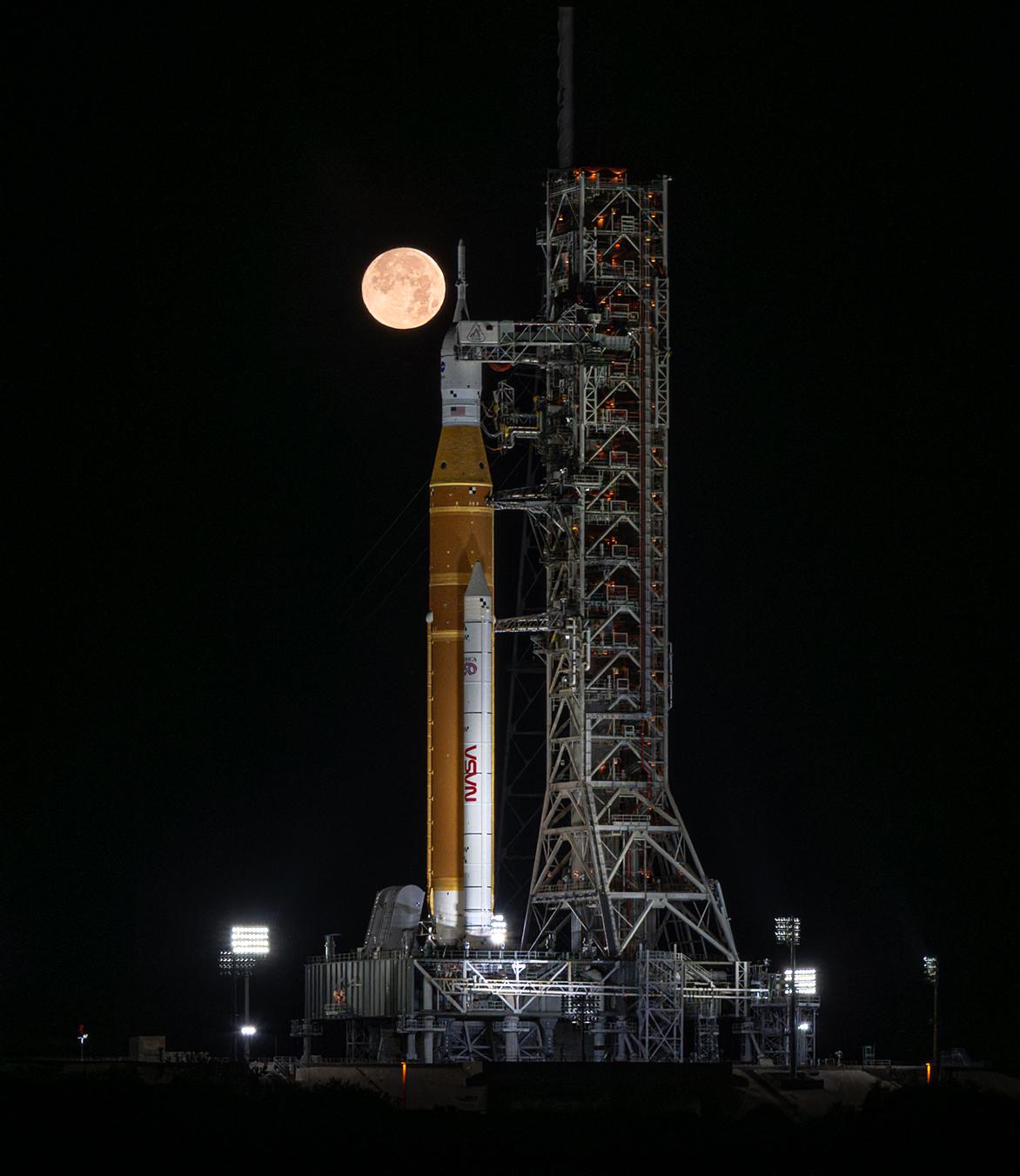 The SLS rocket and Orion spacecraft on the launch pad with the moon behind