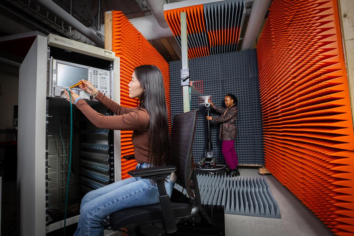 Two people work with instruments in a chamber with gray and orange spiky walls