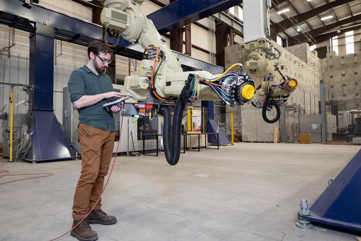 a person in a lab space programs two robotic arms