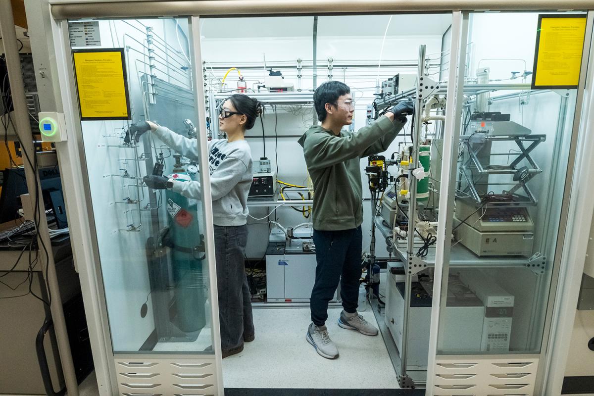 two people set up reactors in a catalyst testing chamber 