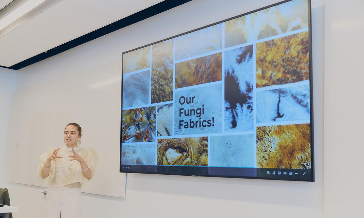 Mya Love Griesbaum presenting a slideshow about her fungi fabrics at the Fashion Insitute of Technology Sustainable Business and Design Conference in April 2026.