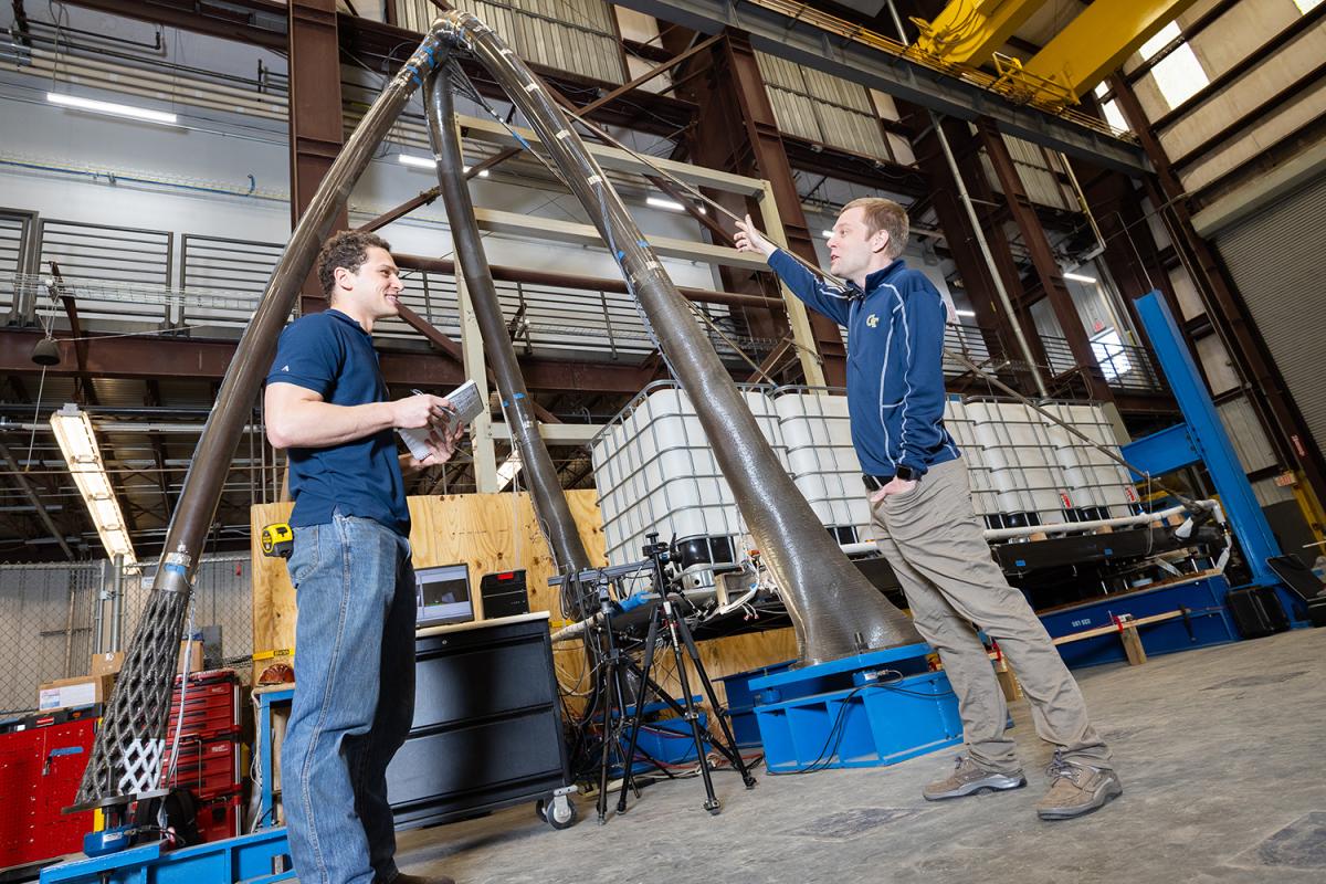 two people in the lab study a tall structure