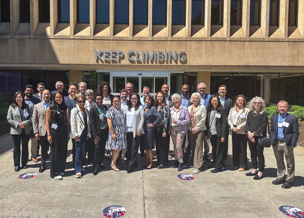 group of people standings in front of building with the slogan "Keep Climbing"