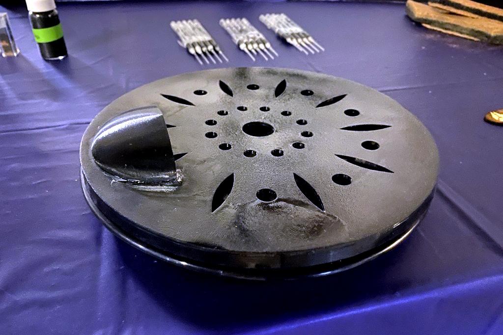 a 3D-printed filter disc on a table in front of vial of biochar material