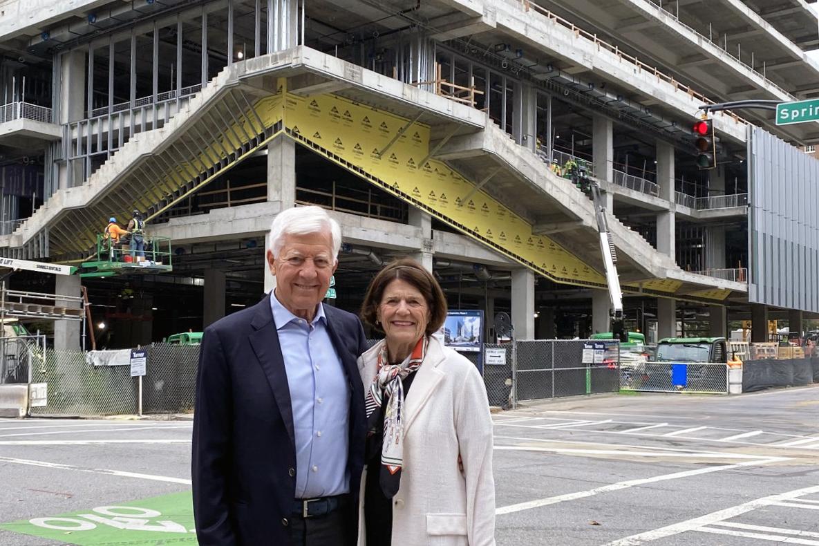Two people stand at street level with a building under construction behind them
