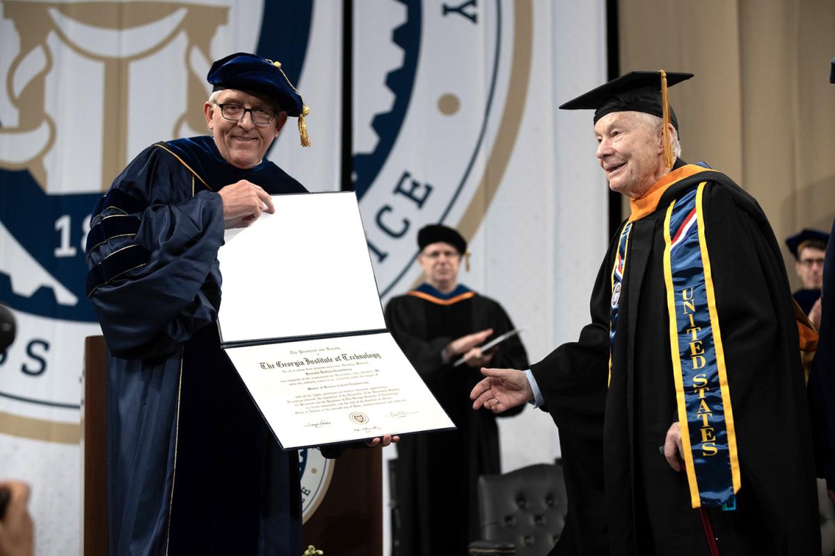 Kenneth Grundborg accepts his master's degree on stage from School of Civil and Environmental Engineering Chair Don Webster.