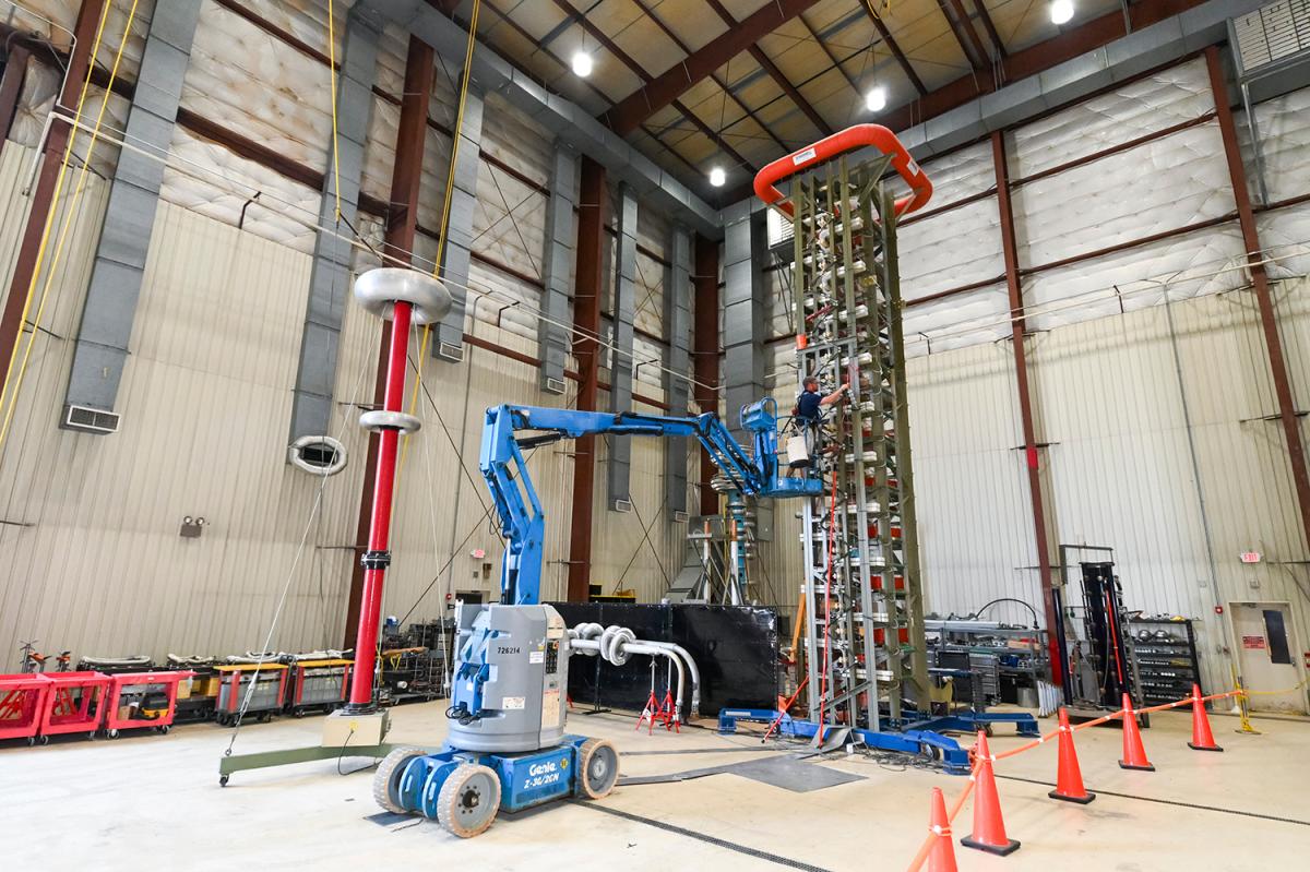 a person on a lift in a warehouse sets up a test on an electrical impulse generator