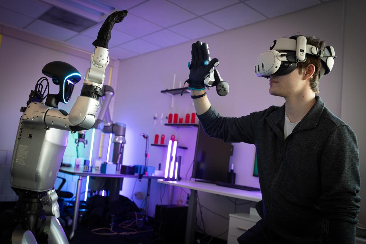 a person wearing a virtual reality headset interacts with a humanoid robot 