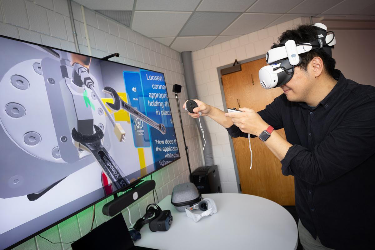 a person wearing a virtual reality headset and handheld devices interacts with a program onscreen