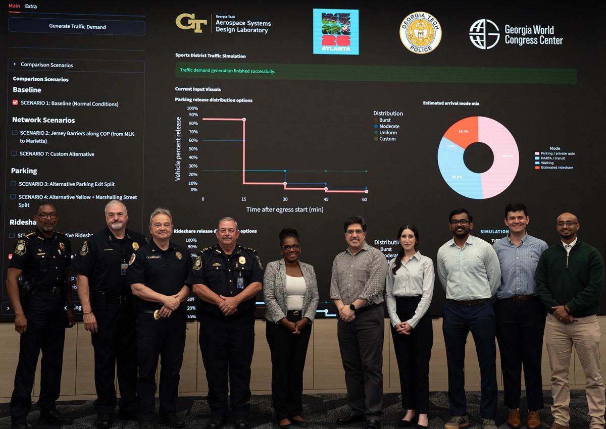 A group of people stands in front of a large screen showing traffic metrics