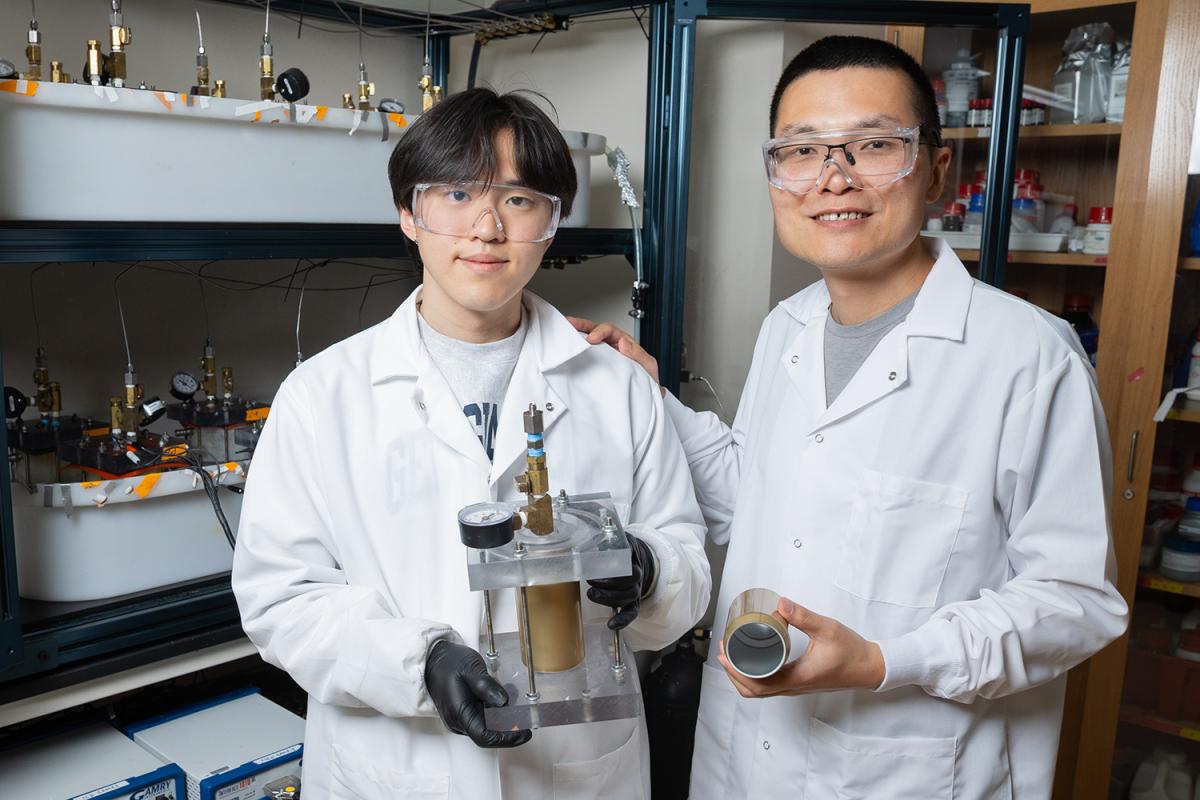 Nian Liu and a student pose with aluminum beverage can testing tools in the lab.