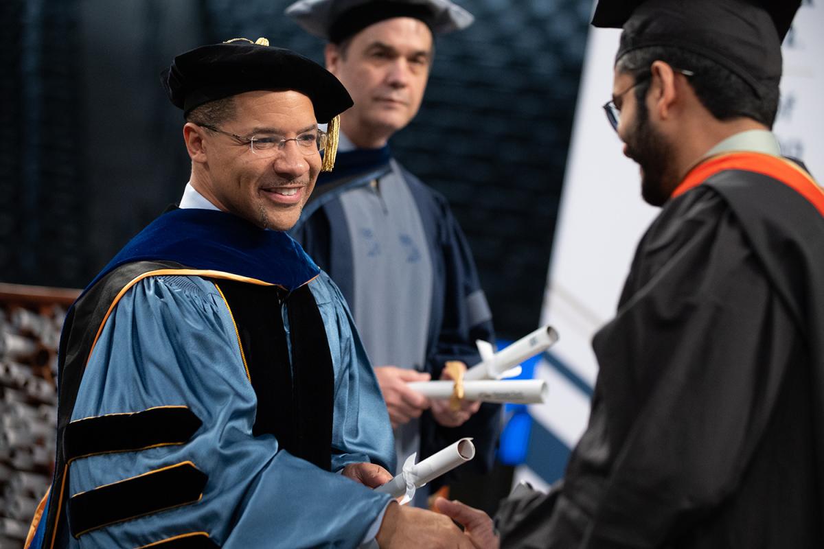 Mitchell Walker shakes a graduate's hand at the Engineering Master's Graduation Celebration.