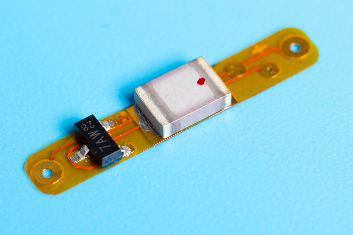 Closeup of a small implant that can communicate wirelessly with external wearables and sensors.