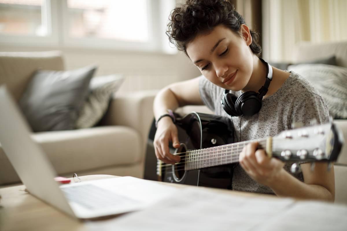 woman playing guitar in front of a computer