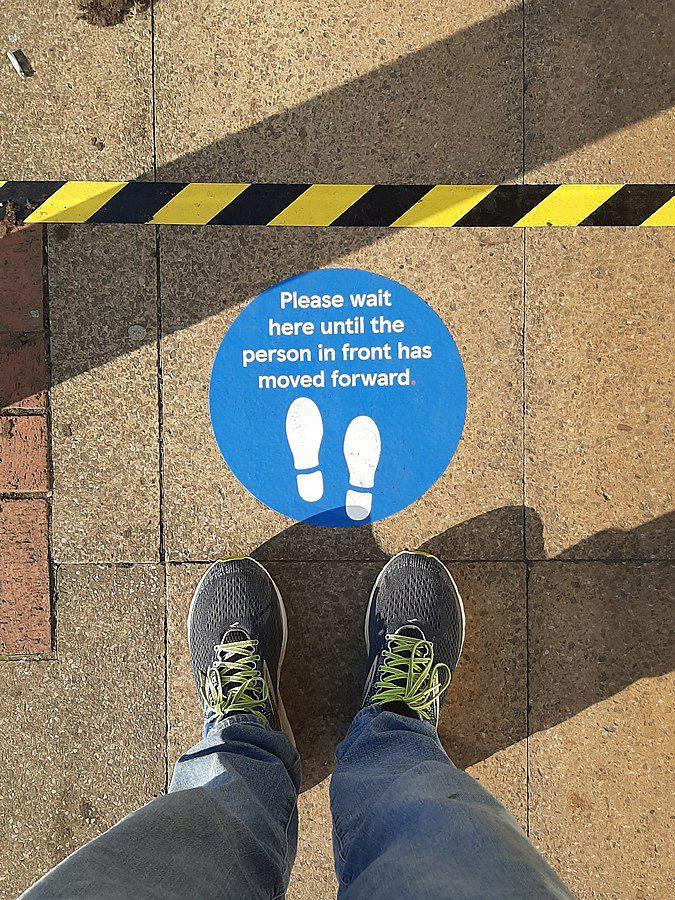 Social distancing vinyl sticker on floor "Please wait here until the person in front has moved forward", photo