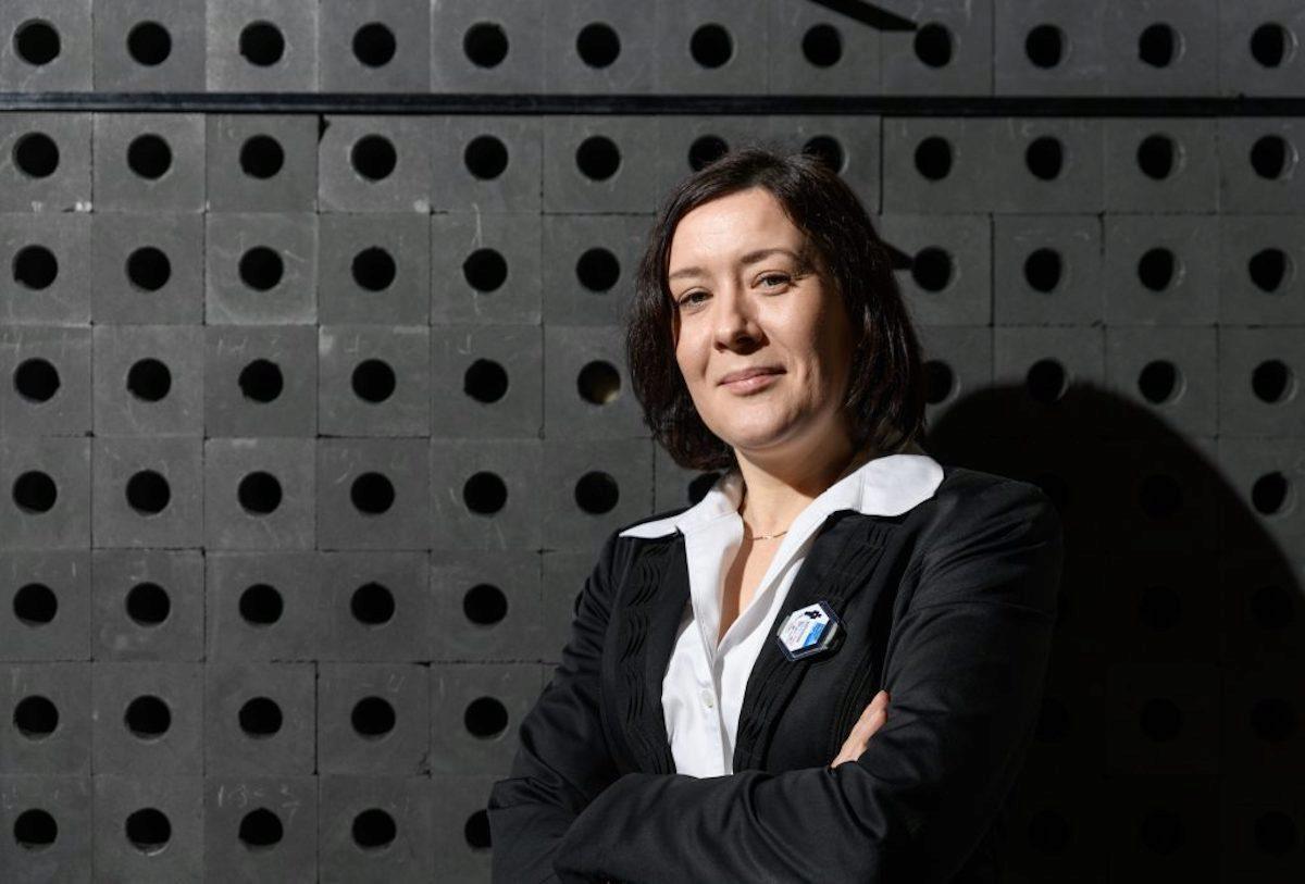 Anna Erickson standing in front of Antineutrino Detection, photo.