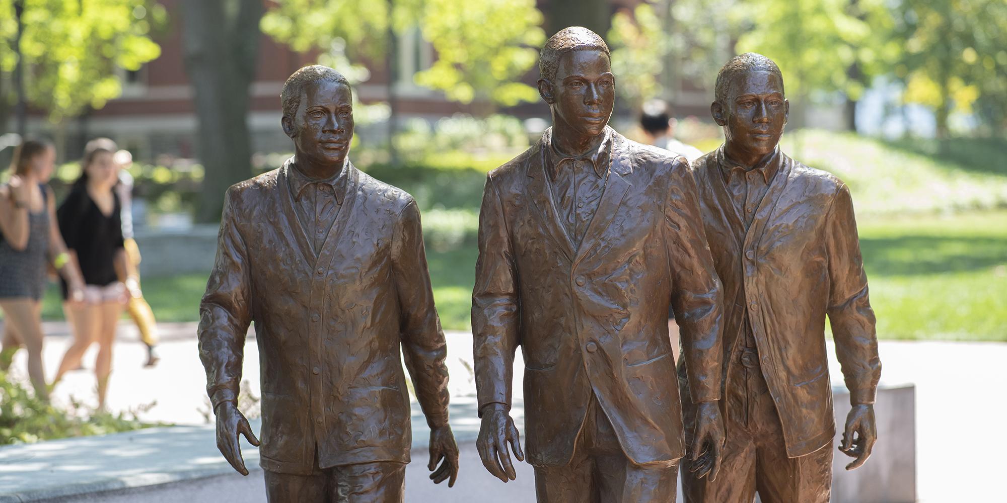 three bronze statues of men in suits