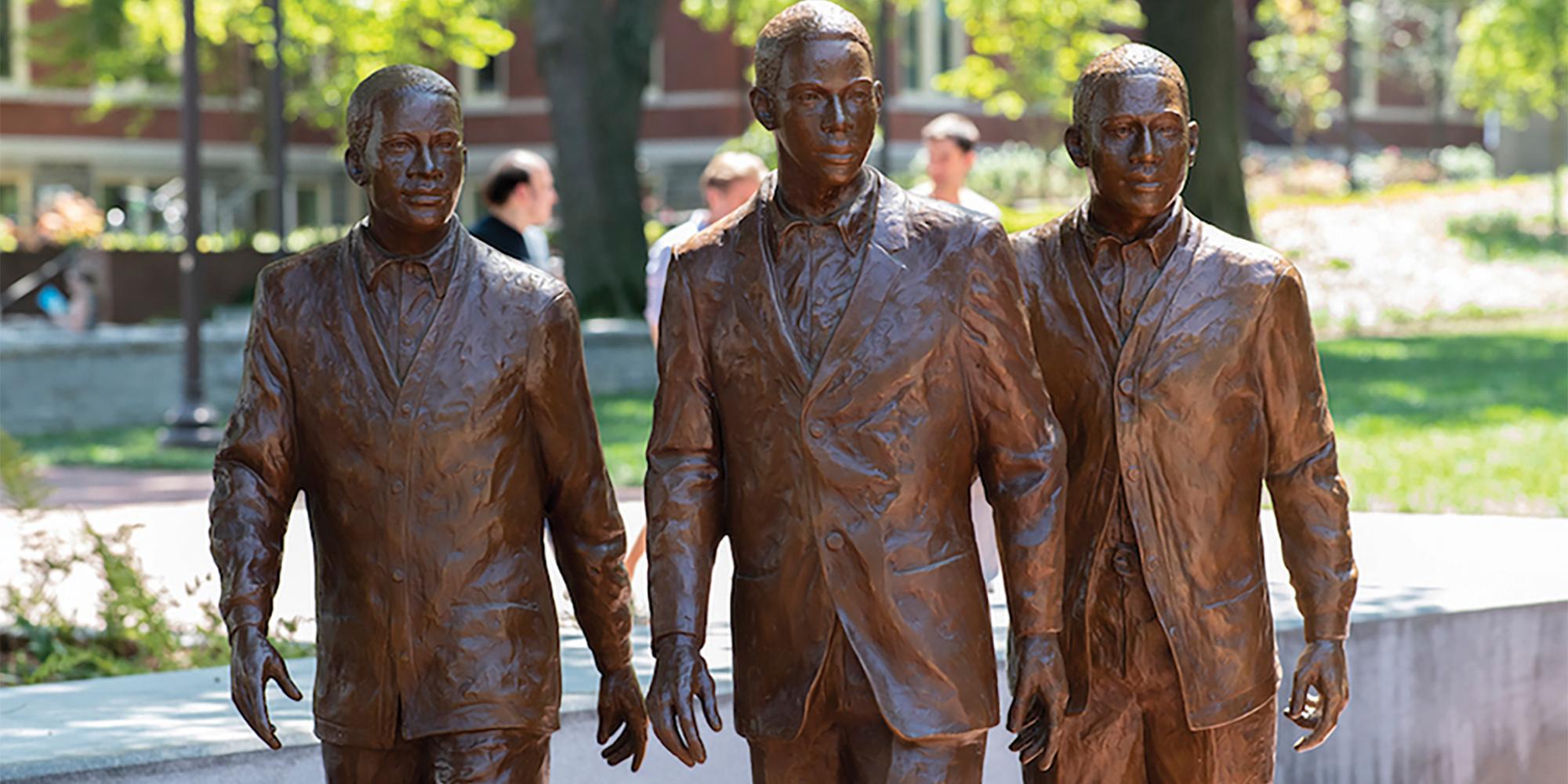 three bronze statues of men in suits