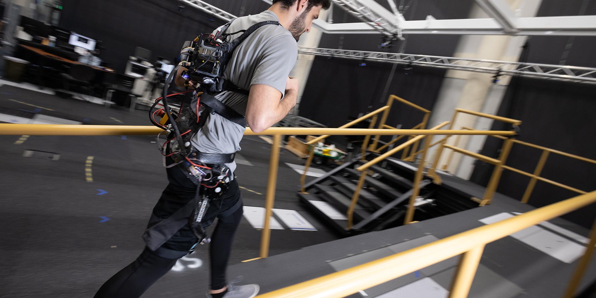 Dean Molinaro walks up a ramp wearing a robotic exoskeleton powered by an AI controller.