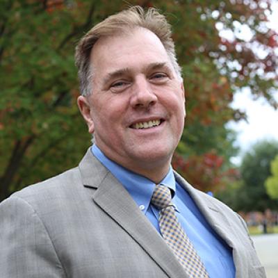 Barry Powell looking at camera in front of a tree