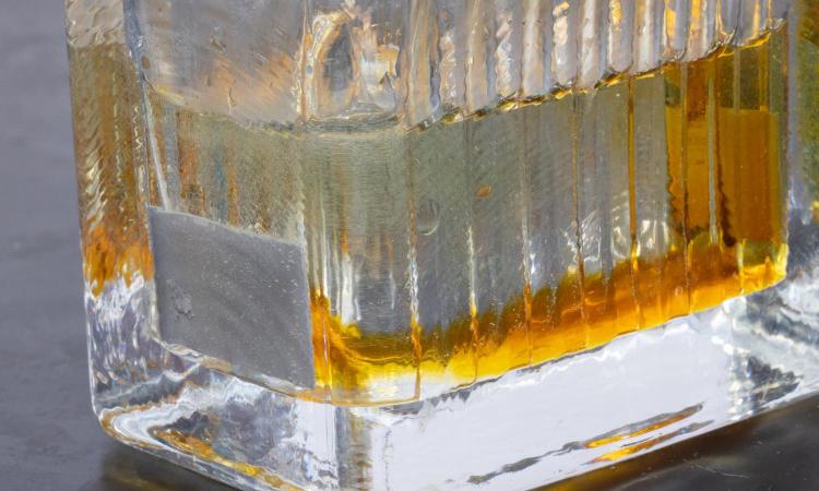 Closeup of a glass container during the stainless steel nano-etching process with orange discoloration in the electrolyte liquid. (Photo: Candler Hobbs)